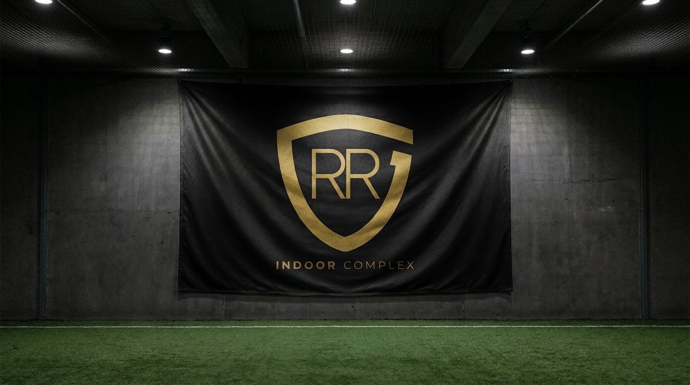 A black and gold RR Indoor Complex banner hanging above the turf